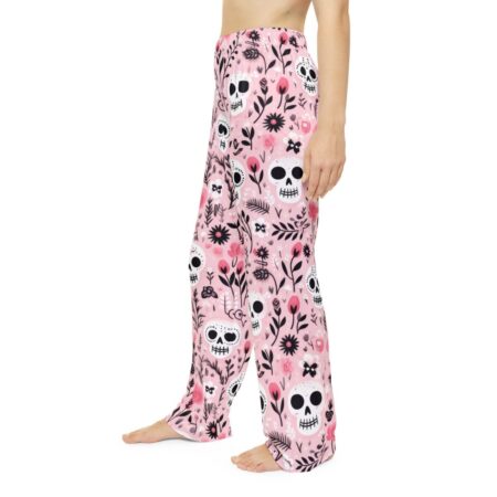 Pink pajama pants with a repeating all-over print of stylized skulls and pink flowers, featuring a seamless wrap-around graphic.