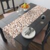 Decorative table runner featuring an all-over print of brown and orange autumn leaves against a white background.