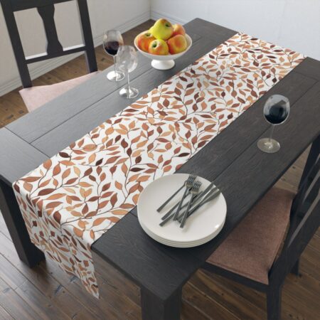 Decorative table runner featuring an all-over print of brown and orange autumn leaves against a white background.