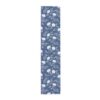 Blue table runner with an all-over white floral pattern, featuring delicate blooming flowers and leaves.