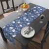 Blue table runner featuring a delicate white floral vine pattern, perfect for dining room decor.