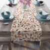 Table runner with a brown and orange leaf pattern on a white background. Perfect for autumn decor.