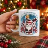White ceramic coffee mug featuring a red buffalo plaid Christmas gnome holding hearts with festive text art.