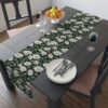 Black table runner with a seamless white daisy floral print and green leaves pattern.