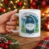 Blue winter gnome print white ceramic mug featuring festive trees and Christmas text slogan artwork.