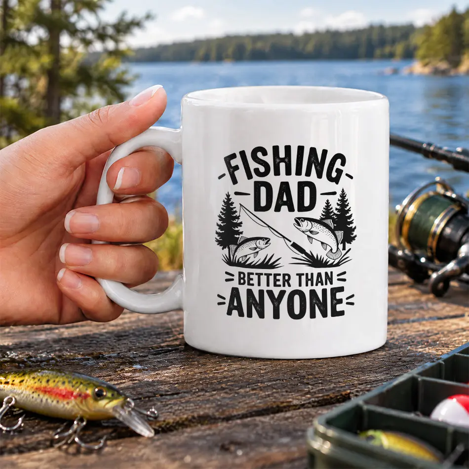 White ceramic coffee mug printed with Fishing Dad Better Than Anyone graphic, pine trees, and leaping trout.