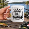 White ceramic coffee mug printed with black Fishing Dad Legacy Runs Deep graphic and fishing rods.