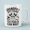 Black skull wearing hat with crossed fishing rods on a white ceramic mug reading Grandpa's Busy Fishing.