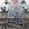 Navy blue table runner with a cream floral and leaf pattern, perfect for a farmhouse or vintage kitchen table setting.