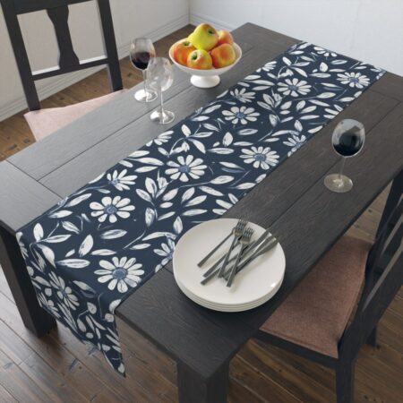 Navy blue table runner featuring a white daisy floral and leaf pattern. A farmhouse decorative accent for dining tables.