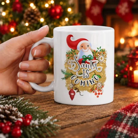 White ceramic mug featuring Santa Claus graphic with Santa Is Coming text and festive Christmas pine and berry accents.